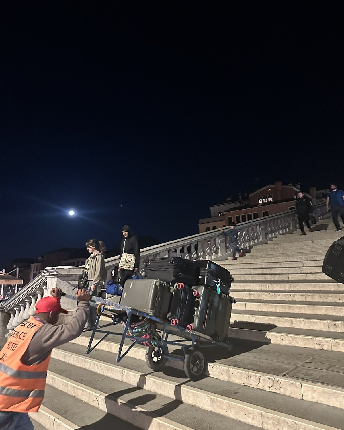 Porter moving luggage up the steps of the Scalzi Bridge in Venice at night